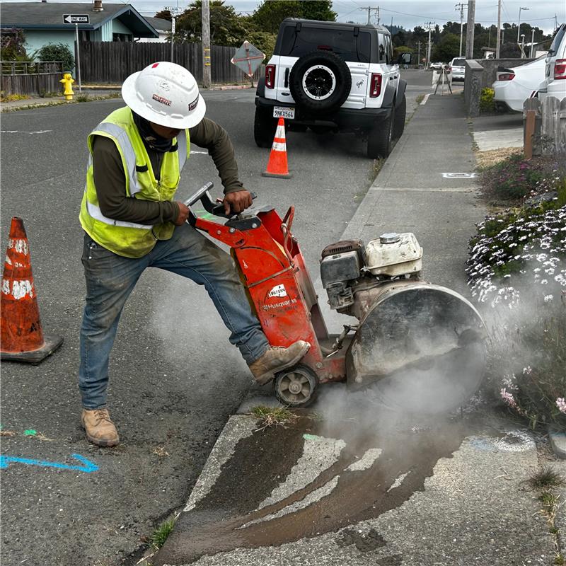 A construction worker uses a saw to cut through concrete.